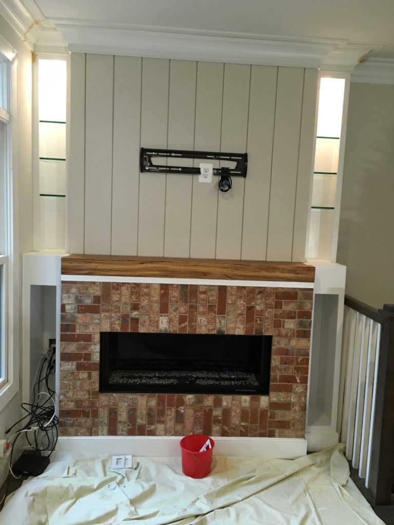 Work in progress shot of Rosslyn fireplace makeover with shiplap and bricks in place