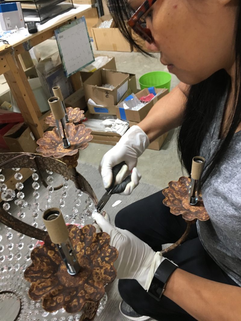 Artisan applying crystal beads by hand to chandelier