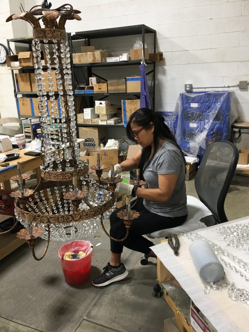 Artisan attaching strings of beads to large Niermann Weeks chandelier