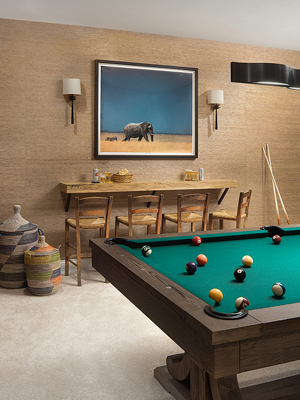 Lower level billiards room design featuring African artwork