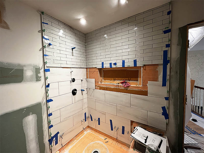 Elongated subway tile and large-format marble tile bathroom shower renovation