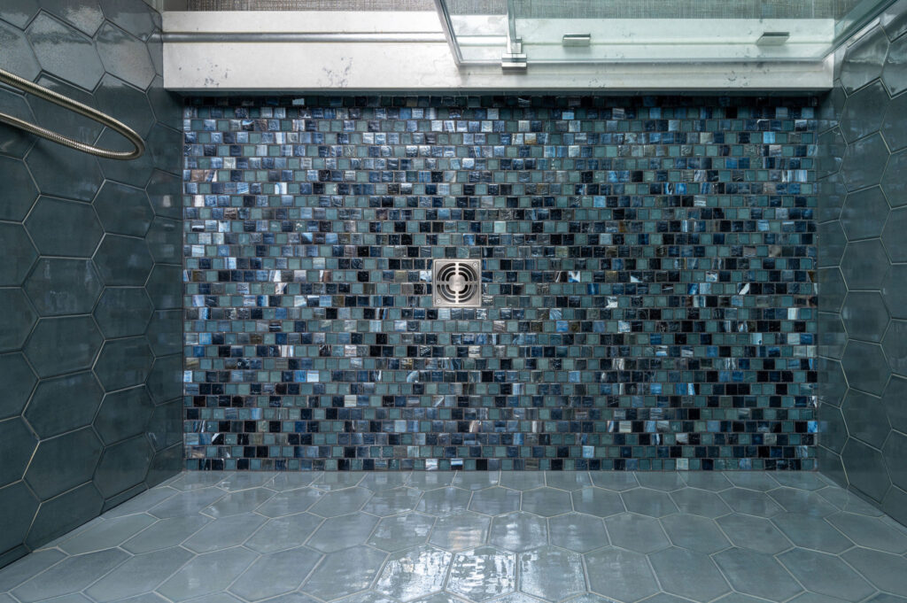 Bathroom shower floor with square mosaic tiles in dark blue.