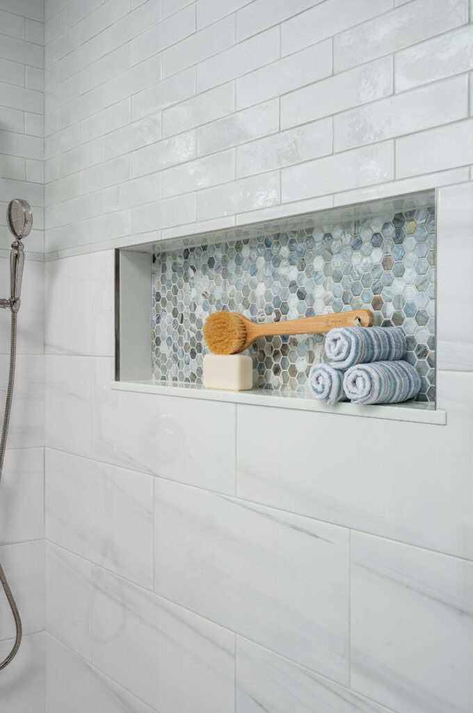 Bathroom shower niche lined with opaque-glass, hexagon tile.