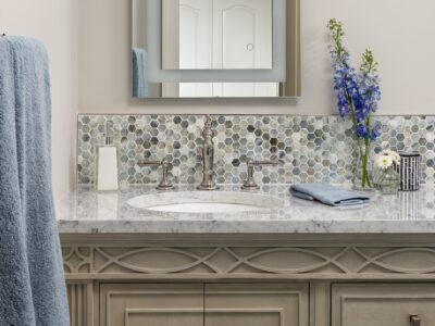 Painted, updated-traditional bathroom vanity with marble countertop, nickel faucet, hexagon mosaic backsplash tile, lighted mirror.