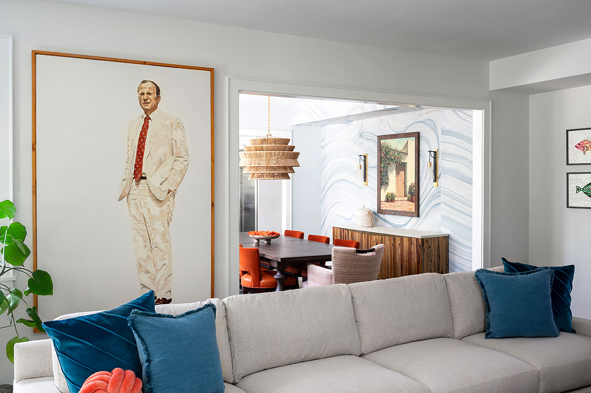 Family room opening to dining room through large cased opening; family portraiture on walls