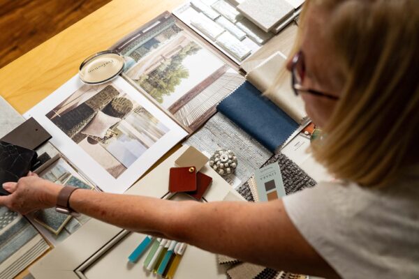 Designer selecting fabric swatches and images from various materials for a creative project on a wooden table.