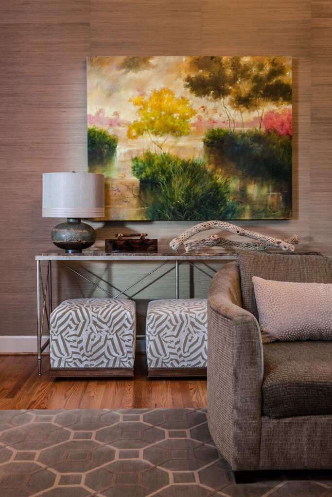 Stylish living room featuring modern art, a decorative table, lamp, and textured seating for a cozy atmosphere.