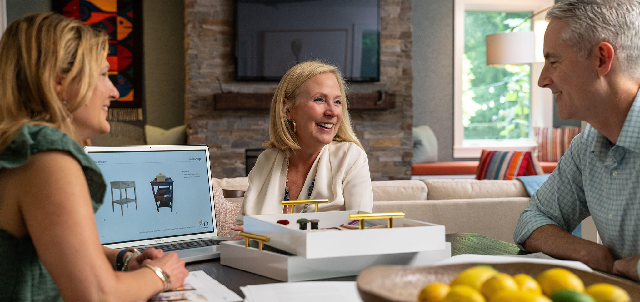 Andrea collaborates with her clients on furniture design in a stylishly decorated living room.