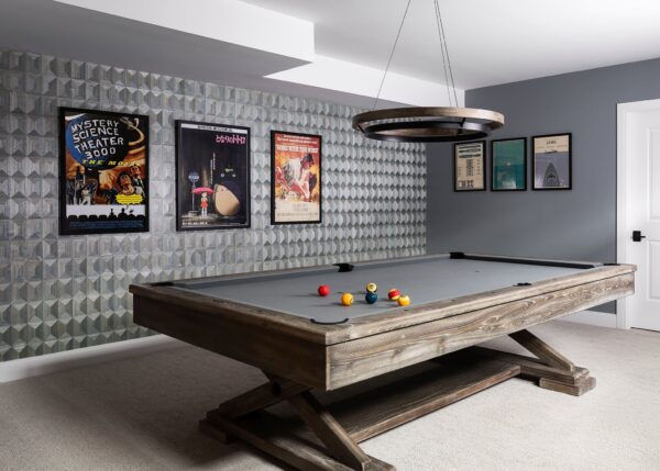 Billiards hangout with pool table with circular light, artwork on wood wallcovering.