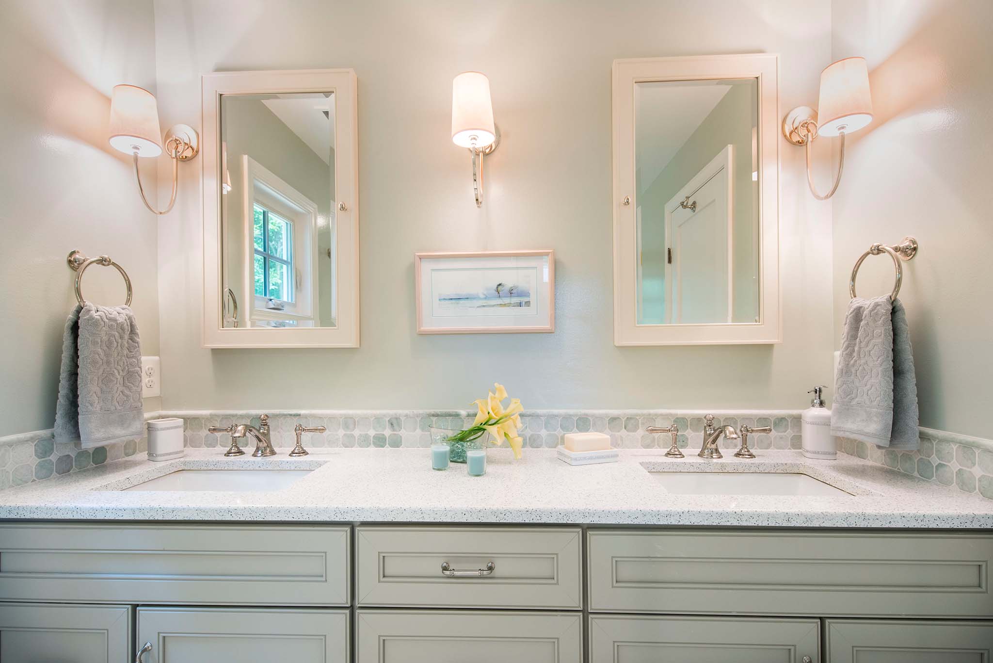 Double vanity bathroom with wall-mounted sconces flanking mirrors.