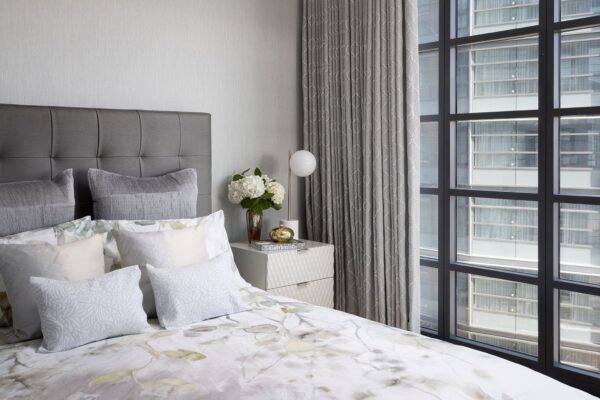 Hotel-style bedroom with gray walls and steel-framed windows.