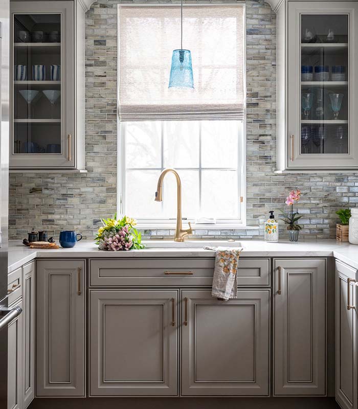 Modern kitchen with gray cabinetry illuminated by natural light.