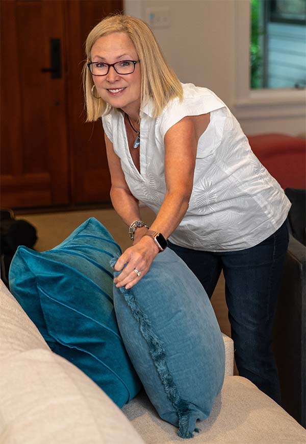 Andrea fluffing pillows on a couch.