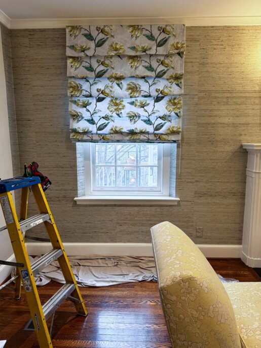 A cozy room featuring floral Roman shades, wooden flooring, and a ladder.
