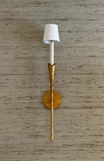 Elegant wall sconce with a textured gold design and a white lampshade on a minimalistic background.