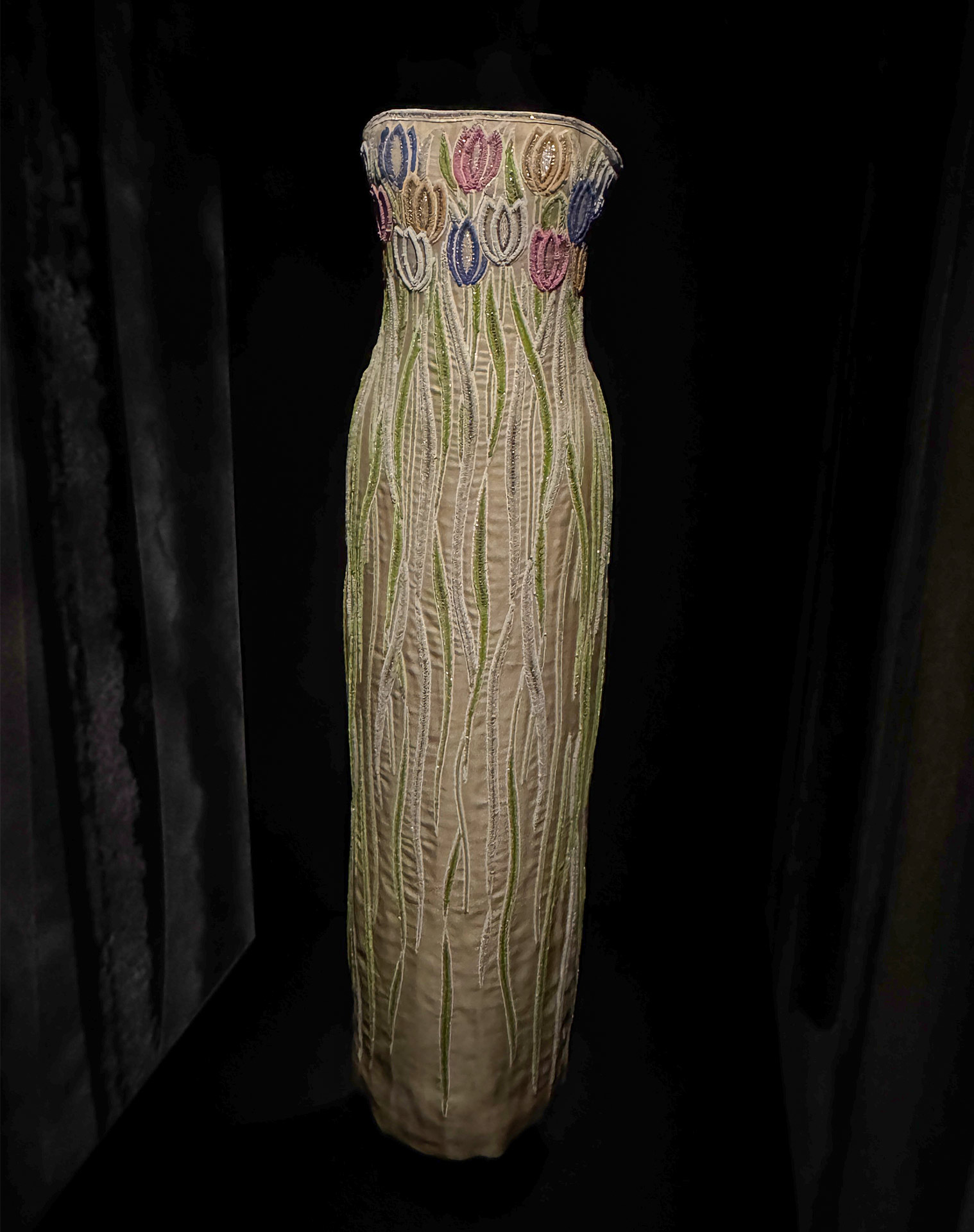 Elegant embroidered dress with floral patterns, showcasing intricate designs in vibrant colors against a dark background.