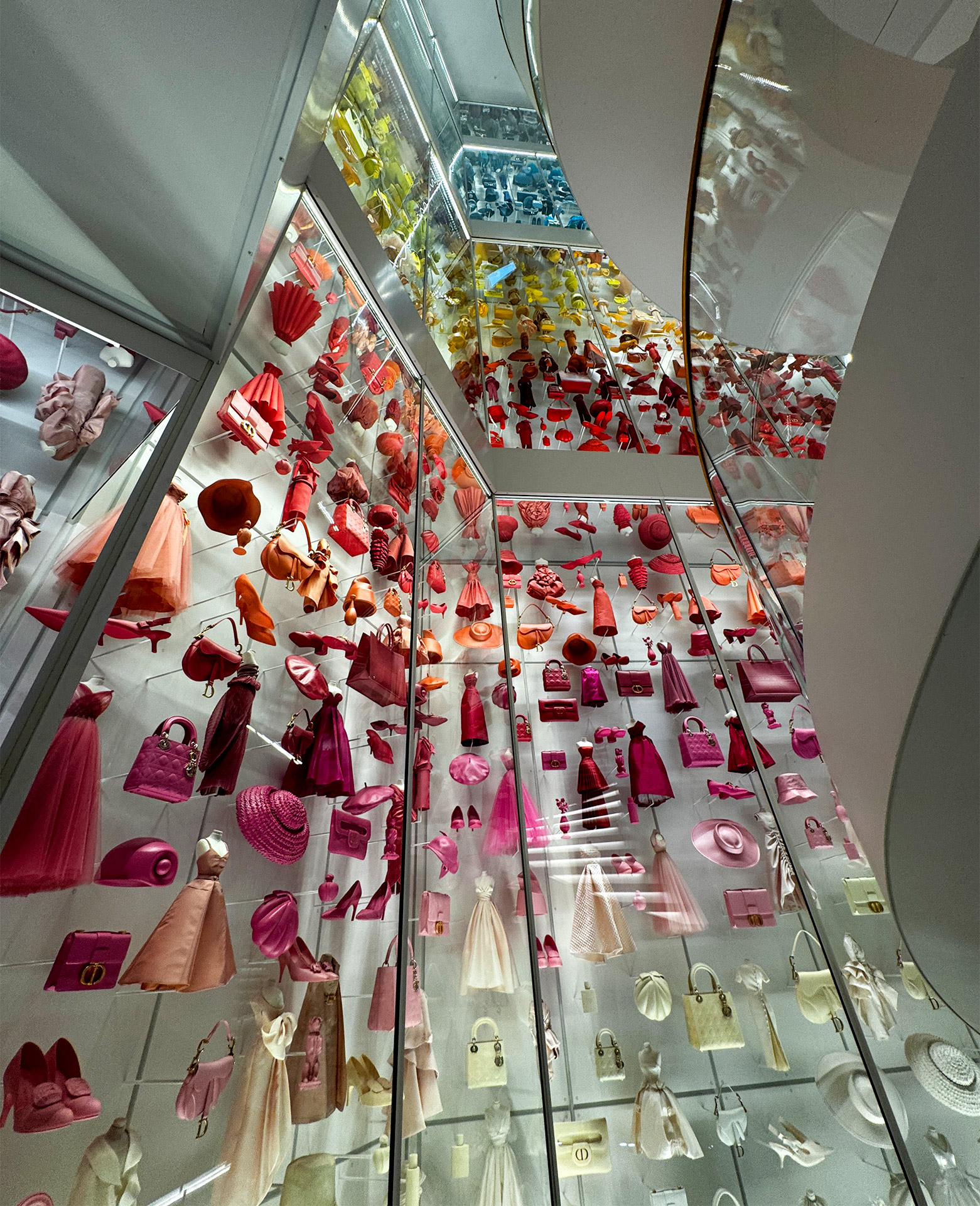 Colorful display of fashion accessories and dresses in a museum exhibit showcasing vibrant textiles and design elements.