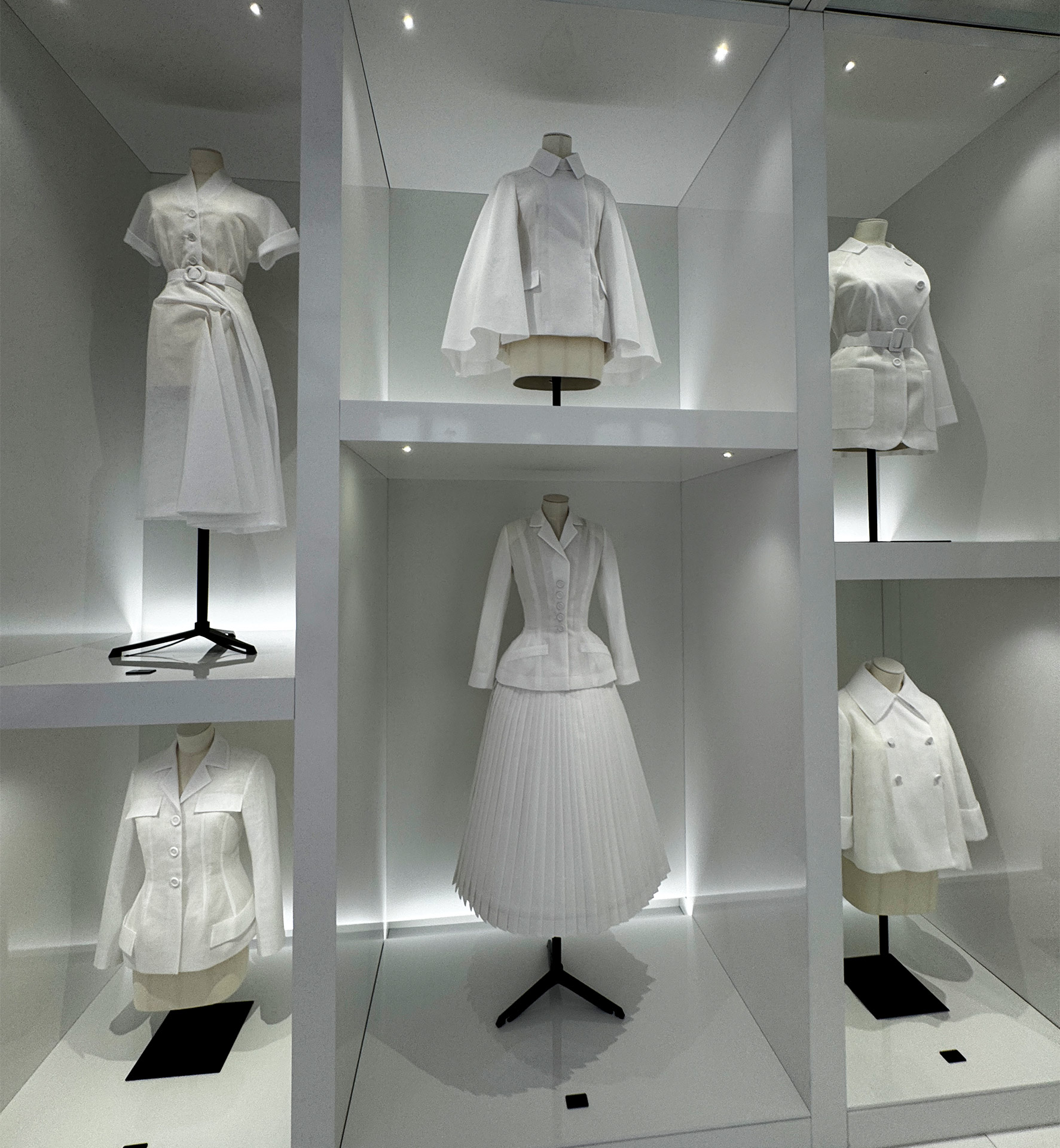Showcase of elegant white fashion designs displayed in modern exhibition cases.