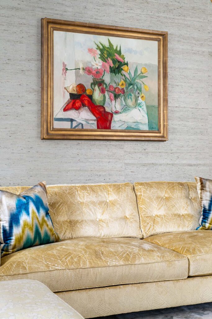 Elegant living room with a gold sofa and a vibrant floral painting above, enhancing the modern decor.