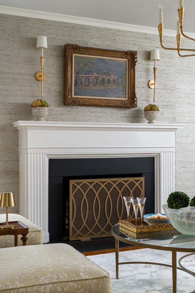 Elegant living room with a classic fireplace, golden accents, and a beautiful painting above.