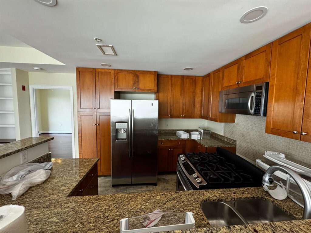Modern kitchen with wooden cabinets, granite countertops, stainless steel appliances, and a double sink.