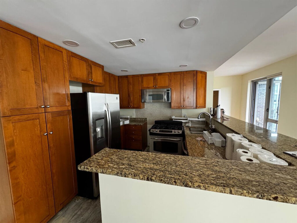 Modern kitchen with wooden cabinets, granite countertops, stainless steel appliances, and ample natural light.